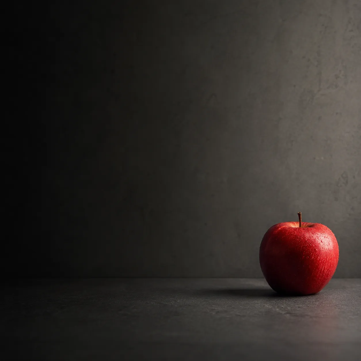 Composición minimalista con una pequeña manzana roja colocada en el lado derecho que equilibra un gran espacio sombreado en el lado izquierdo.